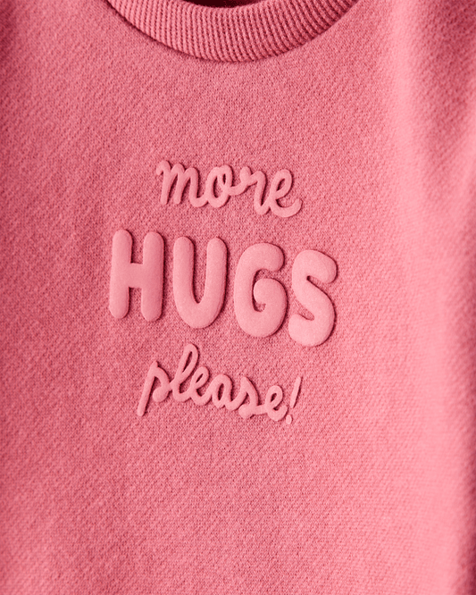 Sudadera rosa con mensaje “More Hugs Please”