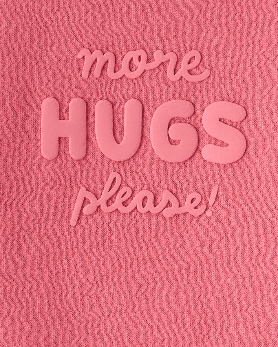 Sudadera rosa con mensaje “More Hugs Please”